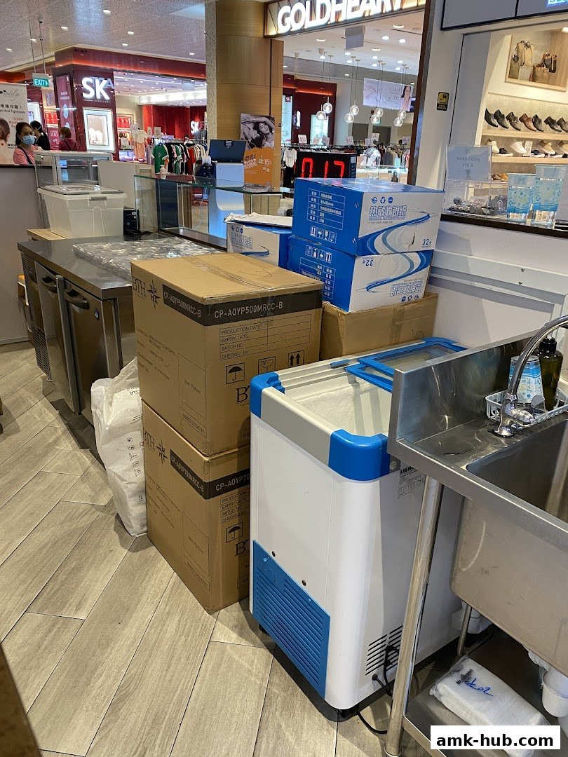 A view of a shop's back area with boxes, a cooler, and a sink.