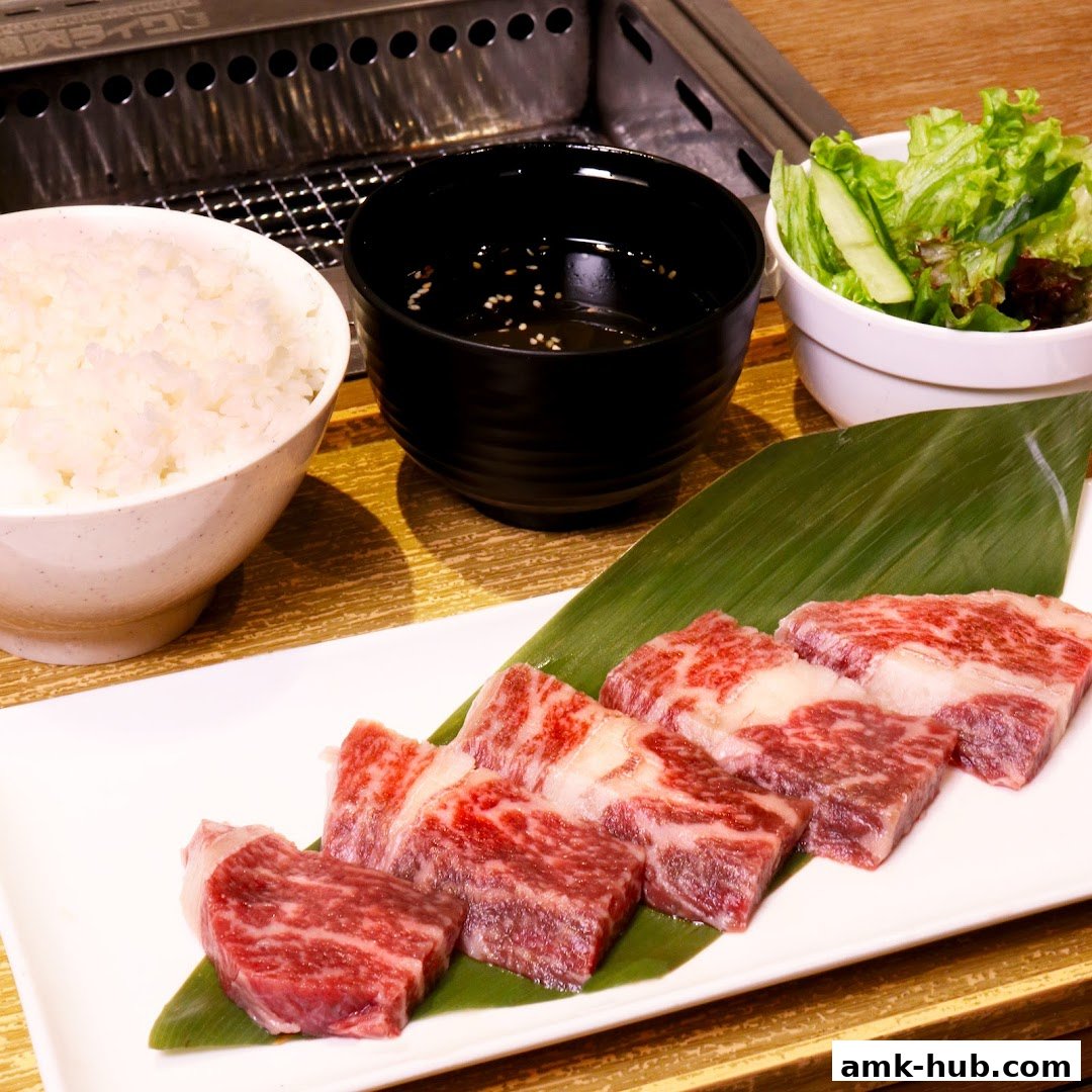 A plate of premium raw beef slices with rice, dipping sauce, and a side salad.