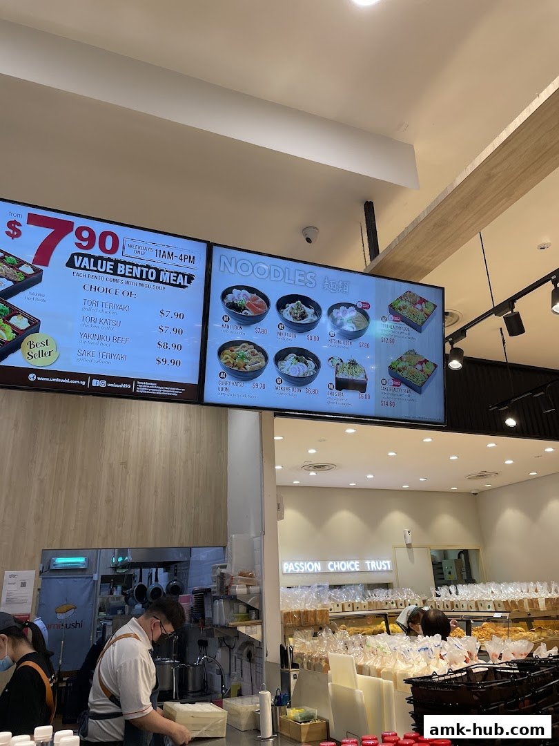 A digital menu board displaying bento meals and noodle dishes with prices.