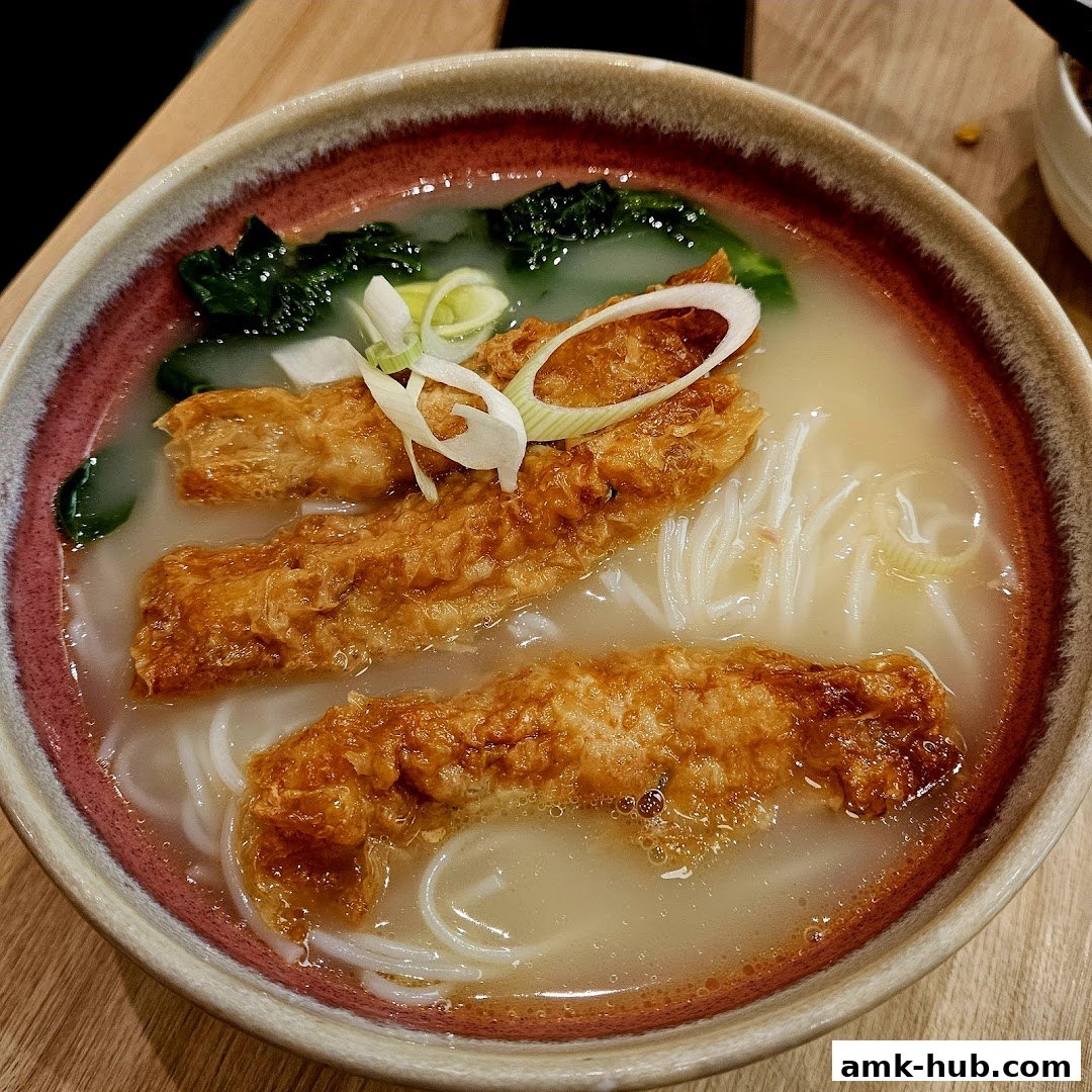 A close-up shot of a delicious bowl of noodle soup with fried tofu and greens.