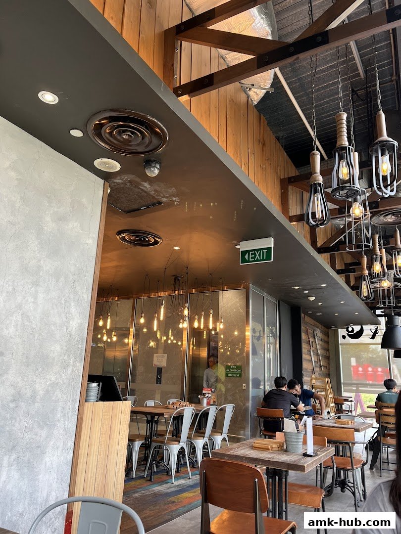 Interior view of a restaurant with wooden accents, industrial lighting, and seating areas.