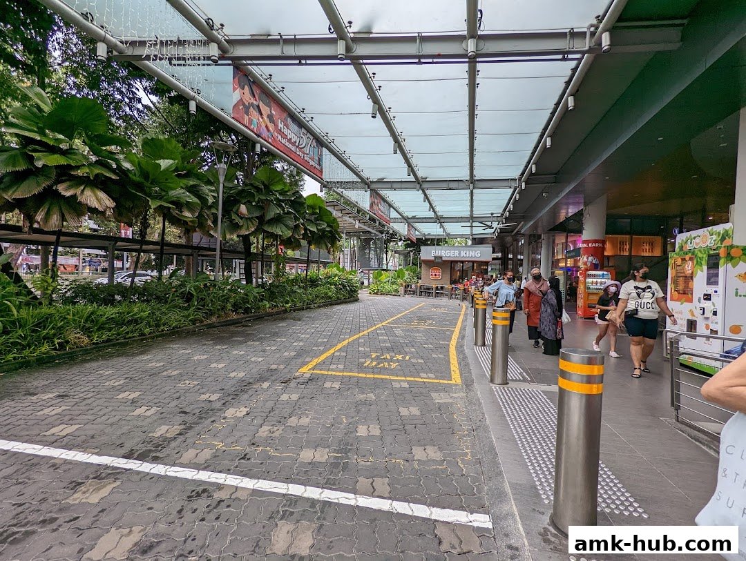 A covered walkway with a taxi stand and various shops, including Burger King.