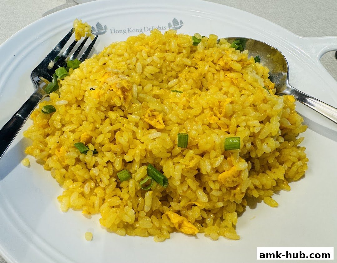 A plate of golden fried rice with chopped green onions and scrambled egg.