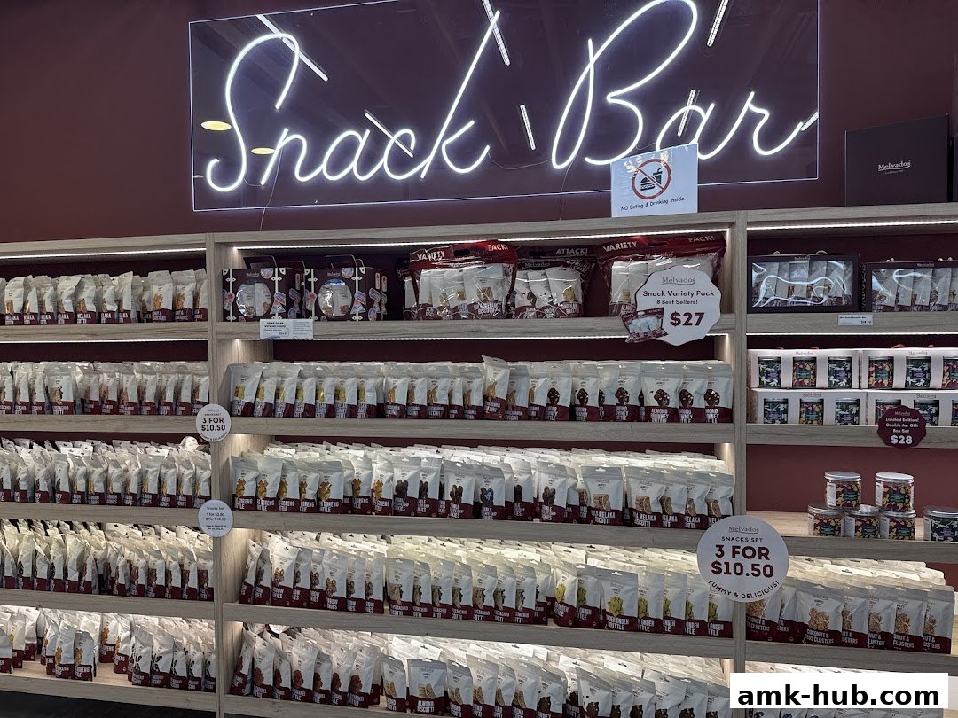 A well-stocked snack bar with shelves full of packaged snacks and a neon 'Snack Bar' sign.