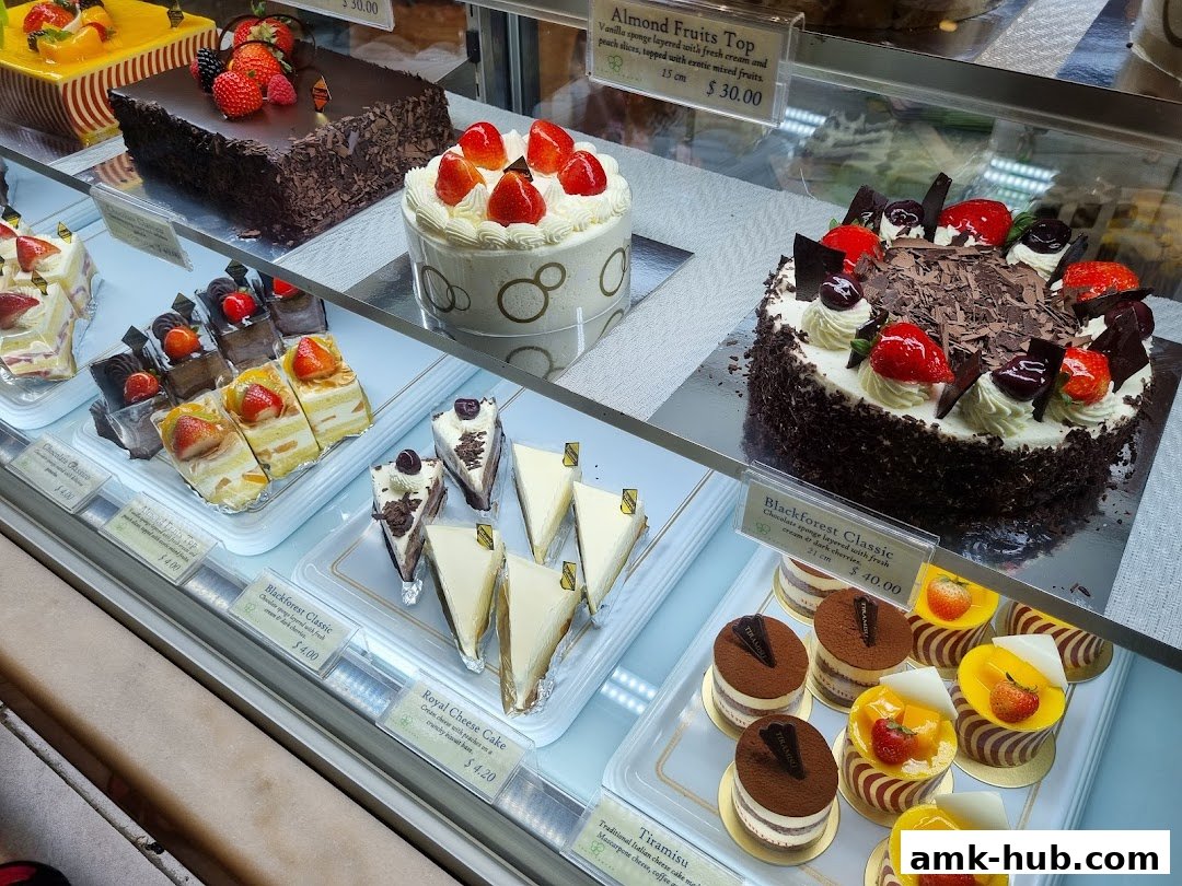 A display case filled with various cakes and pastries, including whole cakes and individual slices.