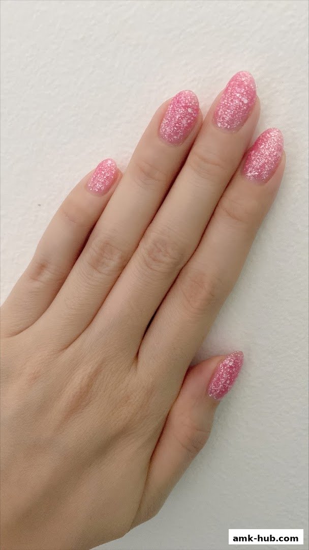 A close-up of a hand with sparkling pink gel nails.