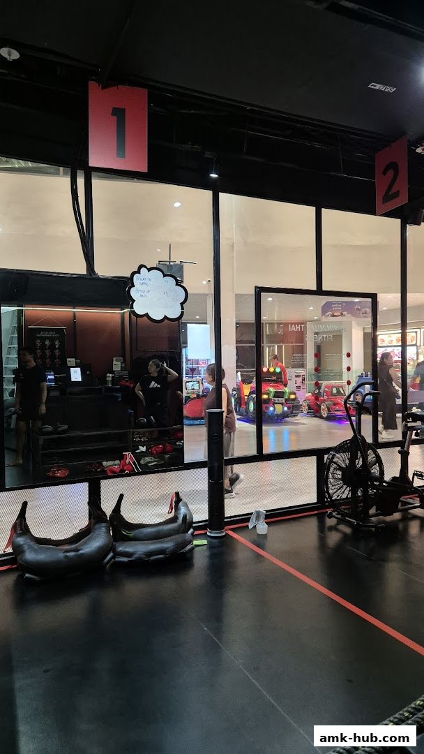 Interior view of a fitness center with training equipment and people inside.