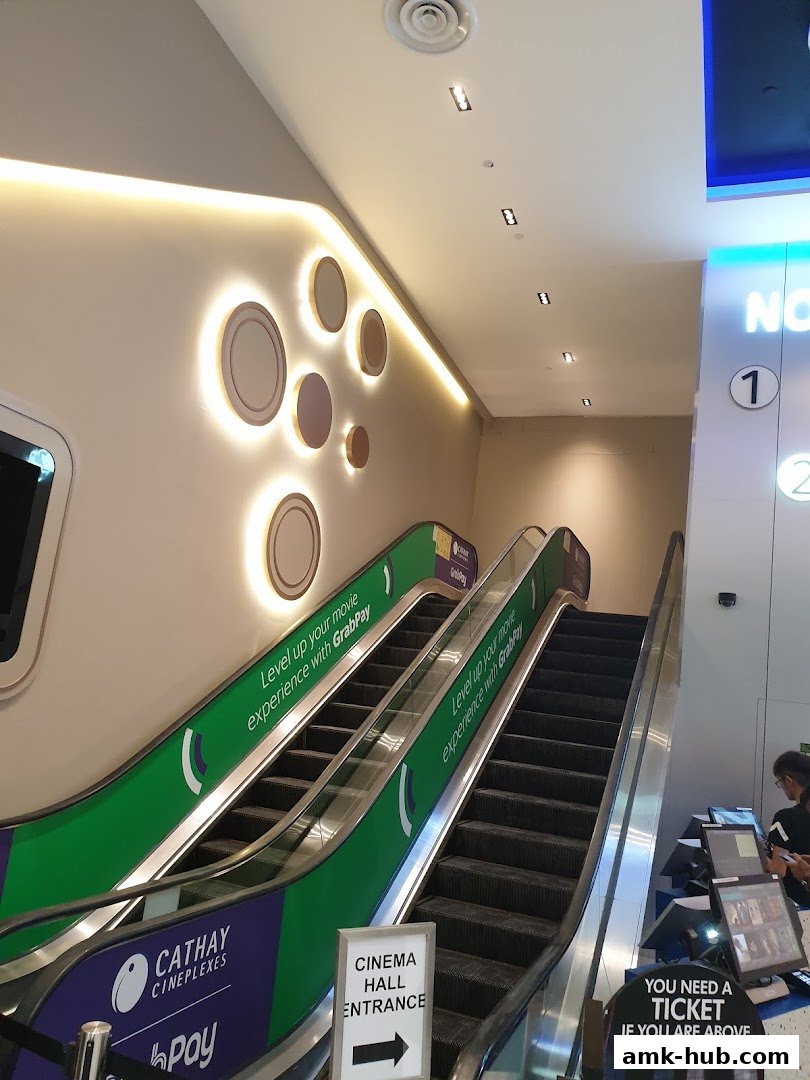 Escalators leading to the cinema hall entrance at Cathay Cineplexes, with promotional signage.