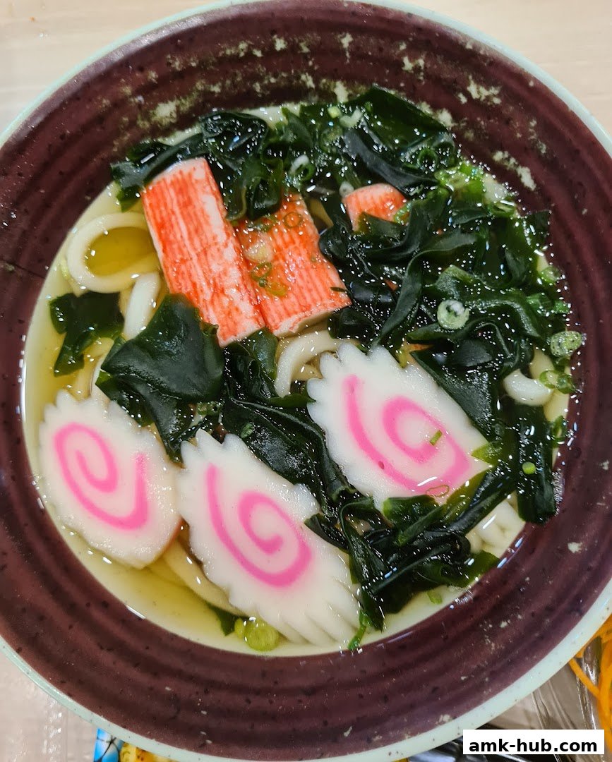 A close-up shot of a delicious bowl of udon noodles with crab sticks and seaweed.