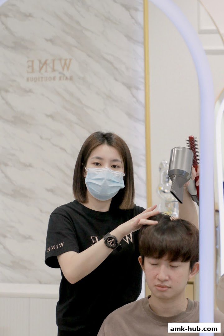 A hairstylist blow-dries a client's hair in a modern salon.