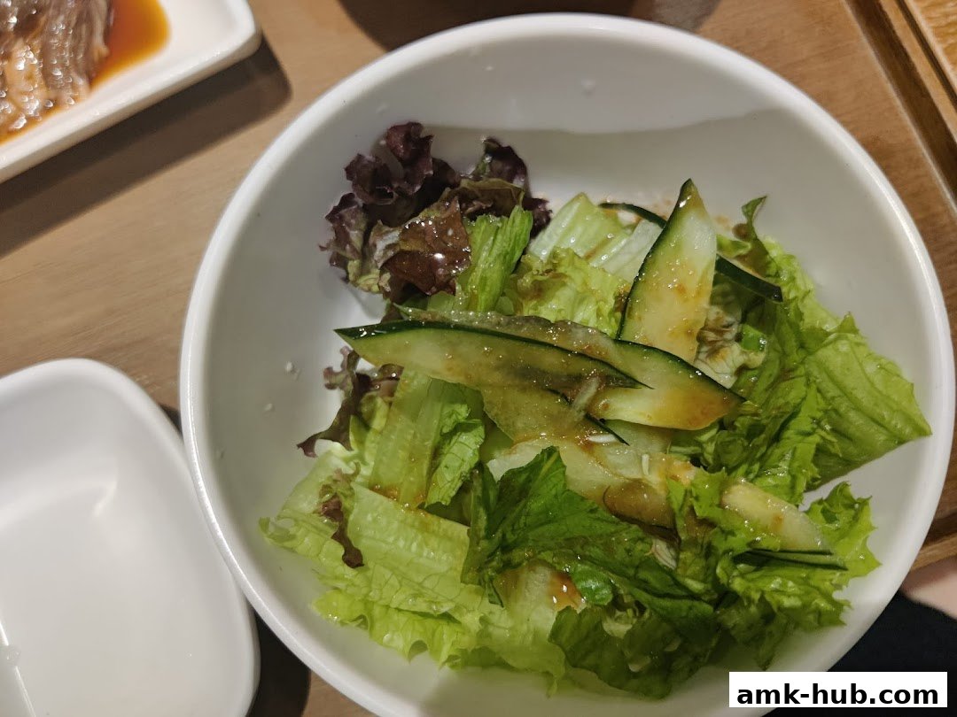 A close-up shot of a fresh salad with lettuce and cucumber in a white bowl.
