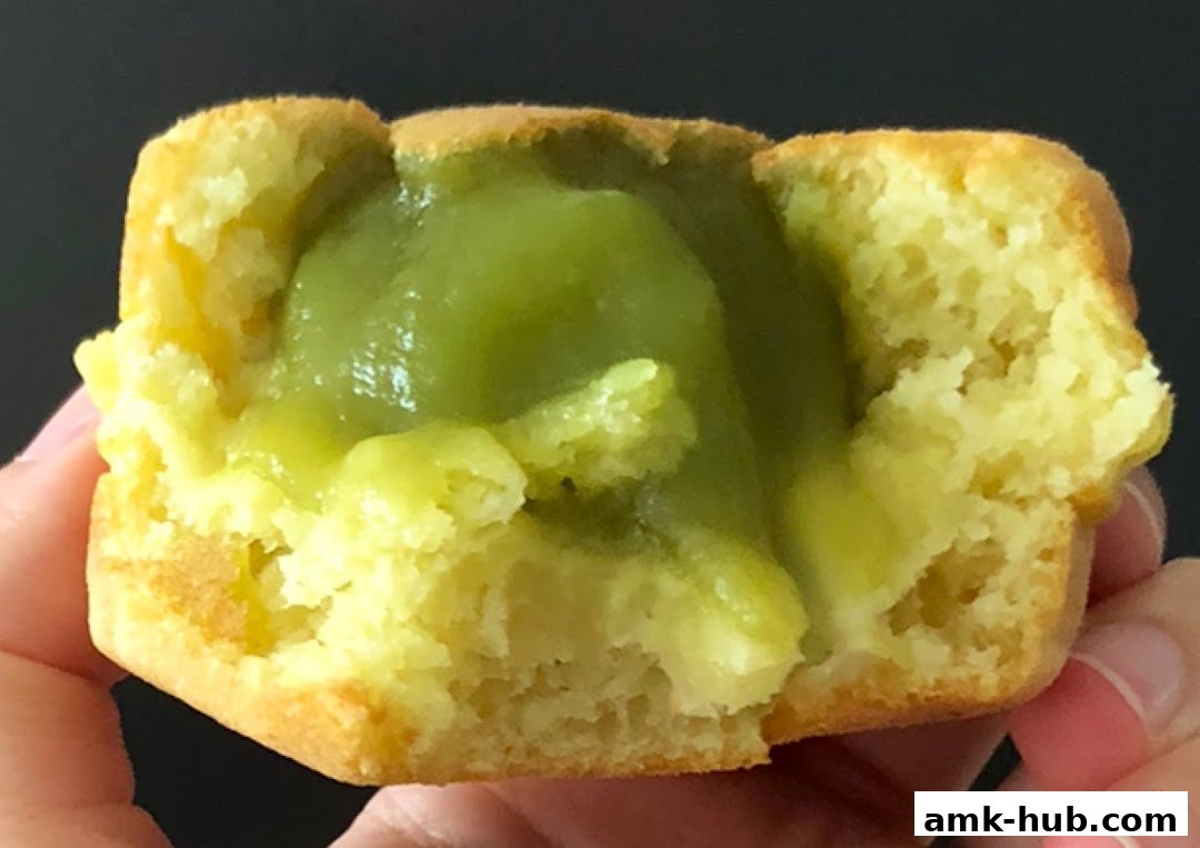 A close-up of a pastry with a green filling, held by a hand.