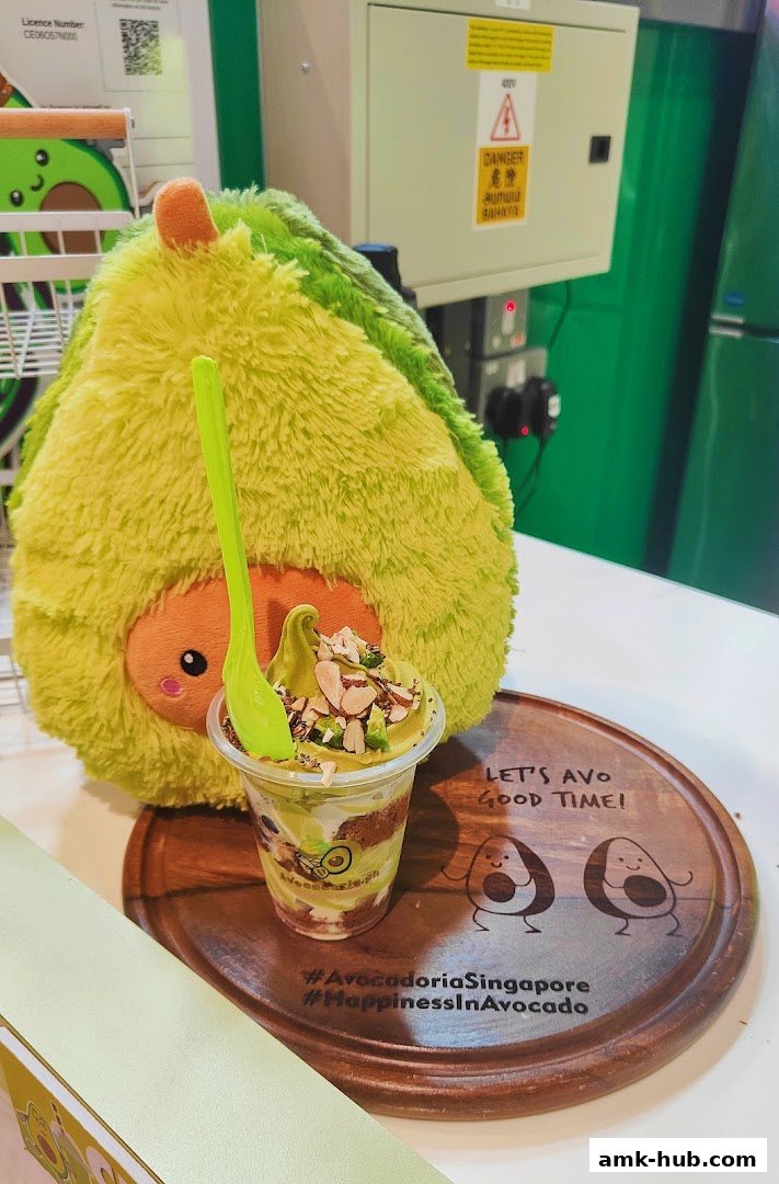 A delicious avocado dessert with toppings and a cute avocado plush toy.