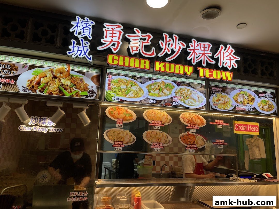 A food stall displaying various dishes with prices and images, featuring Char Kway Teow.