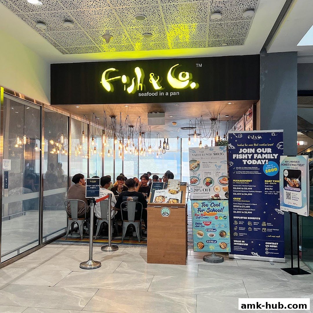 The entrance of Fish & Co. restaurant with a neon sign and customers dining inside.
