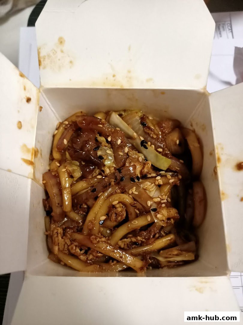 A close-up shot of a takeaway box filled with delicious stir-fried noodles and vegetables.