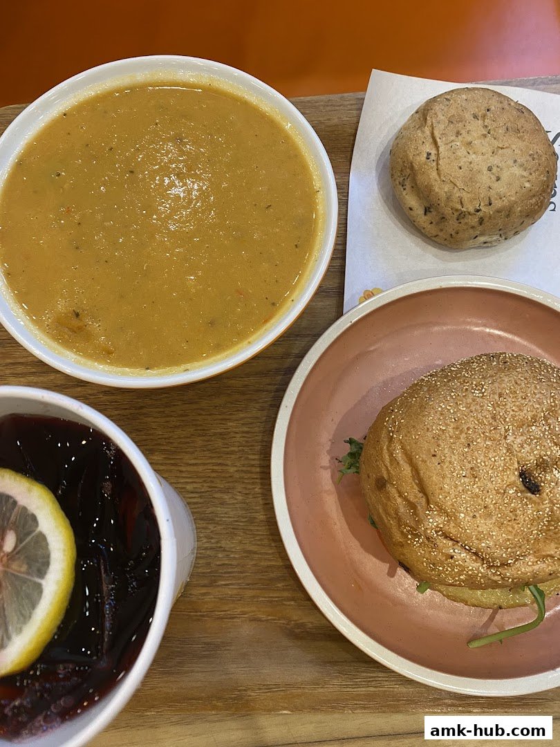 A delicious meal featuring a bowl of soup, a sandwich, and a drink with lemon.