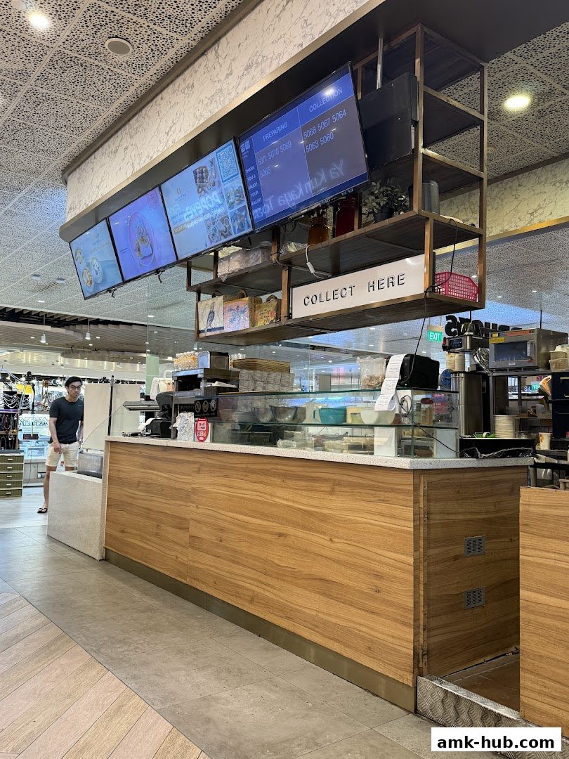 A modern soup shop counter with digital menus and a 'Collect Here' sign.