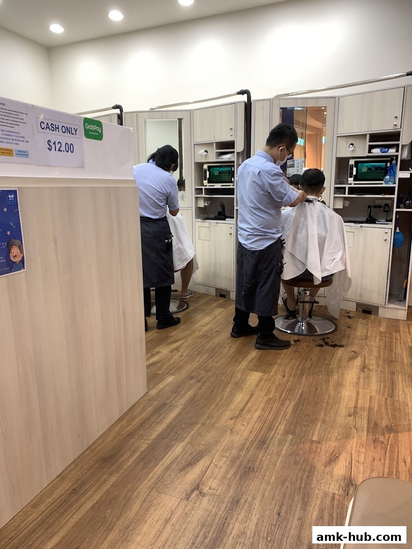 Barbers are cutting hair for customers inside a clean, modern salon.