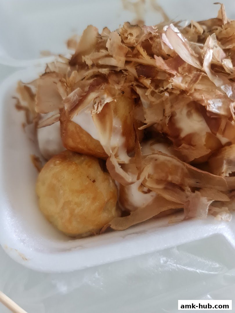 A close-up of delicious takoyaki topped with bonito flakes and sauce.