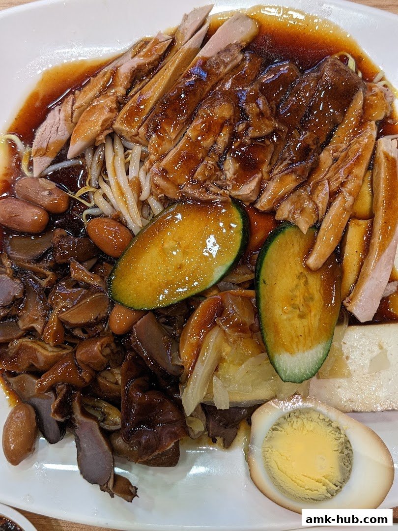 A plate of braised duck rice with various side dishes and a hard-boiled egg.