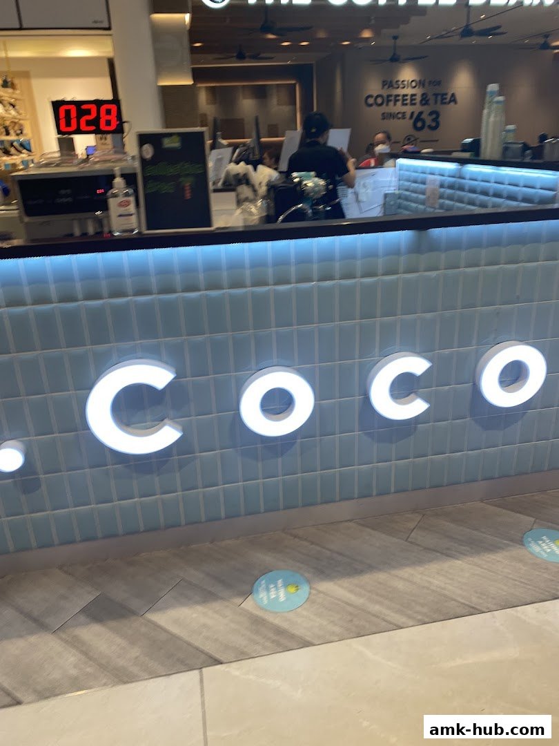 The illuminated 'COCO' logo is displayed on a tiled wall above a counter.