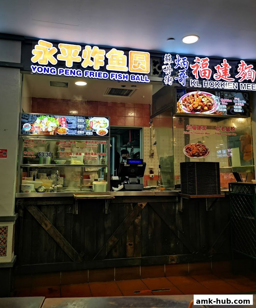 A food stall with bright signage displaying Chinese and English names and pictures of dishes.