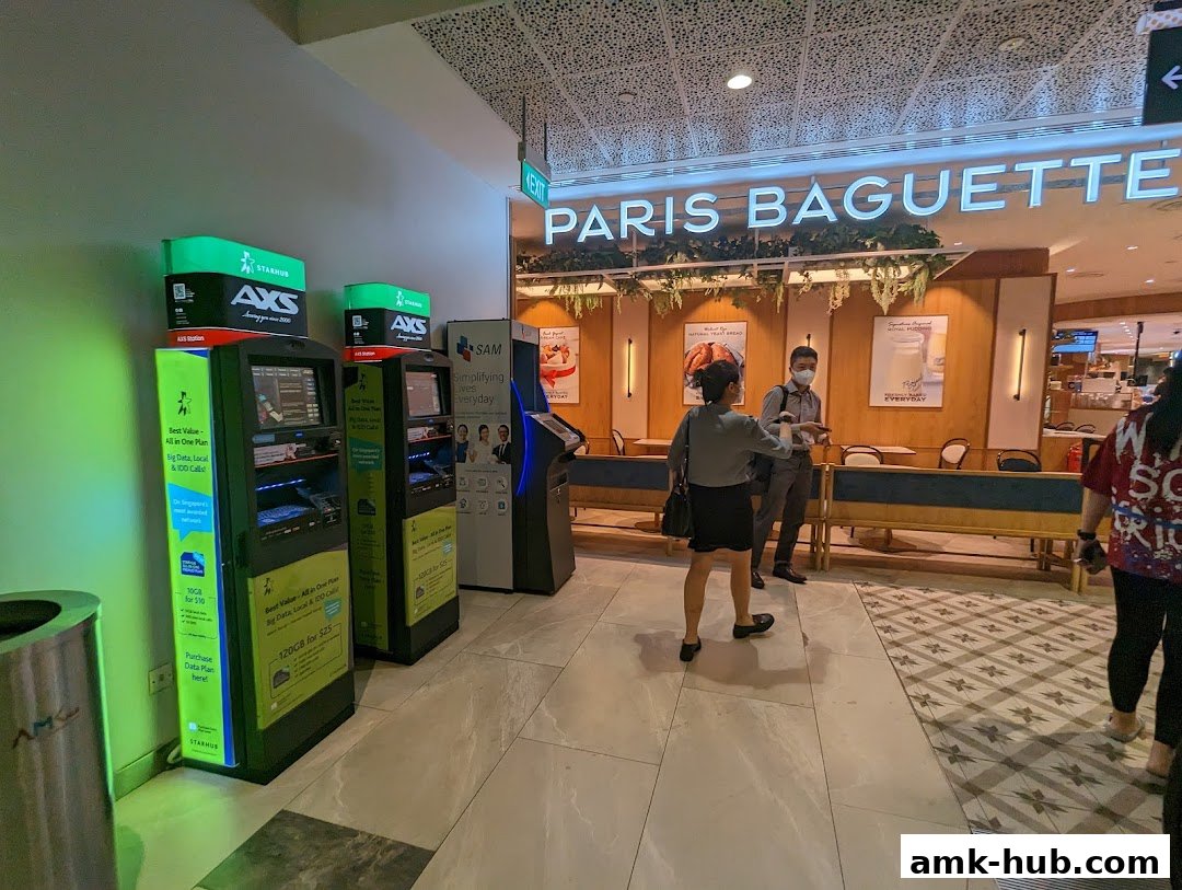 AXS self-service kiosks and a Paris Baguette cafe are visible in a mall.