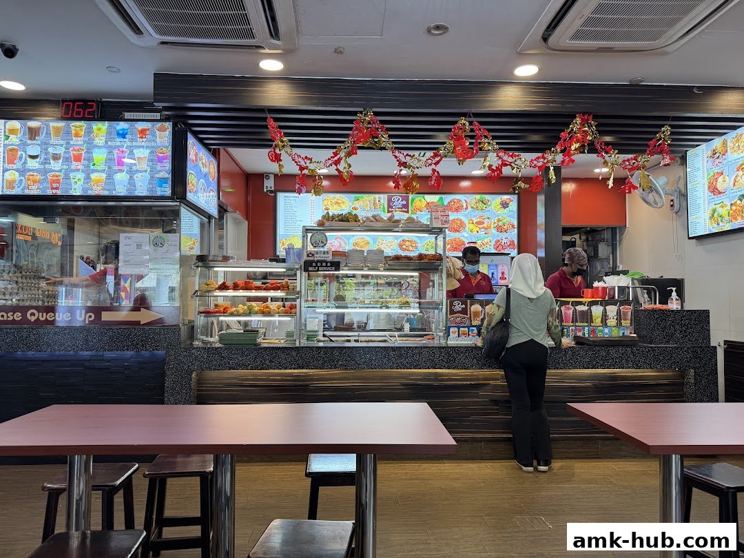 Customers ordering food at a counter with a display of food and drinks.