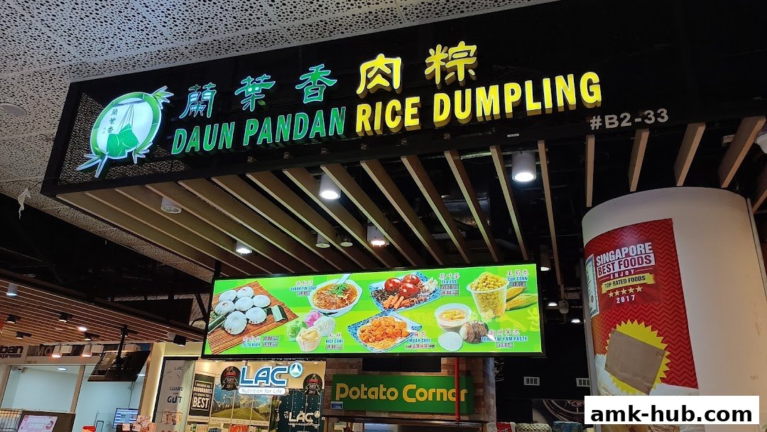The illuminated sign for Daun Pandan Rice Dumpling, showcasing various food items and the shop's location.