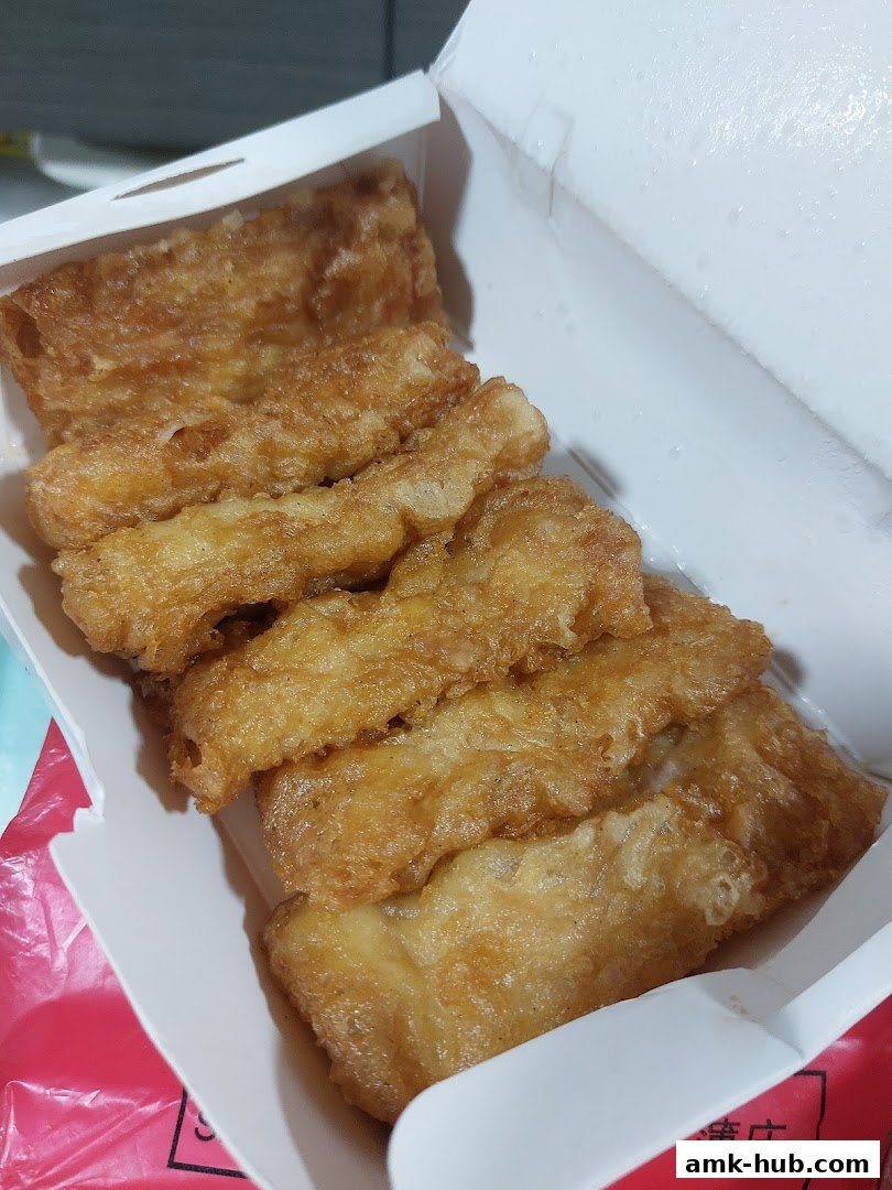 A close-up of crispy fried food items in a white takeout box.