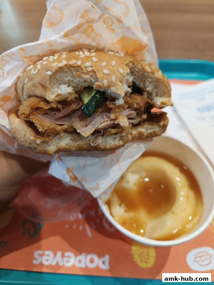 A close-up of a Popeyes chicken sandwich and mashed potatoes with gravy.