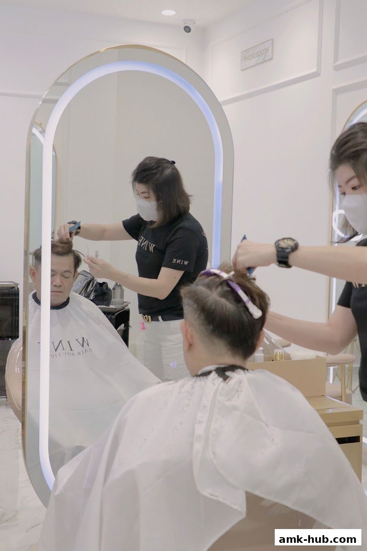 Two stylists are cutting hair for two clients in a bright, modern salon.