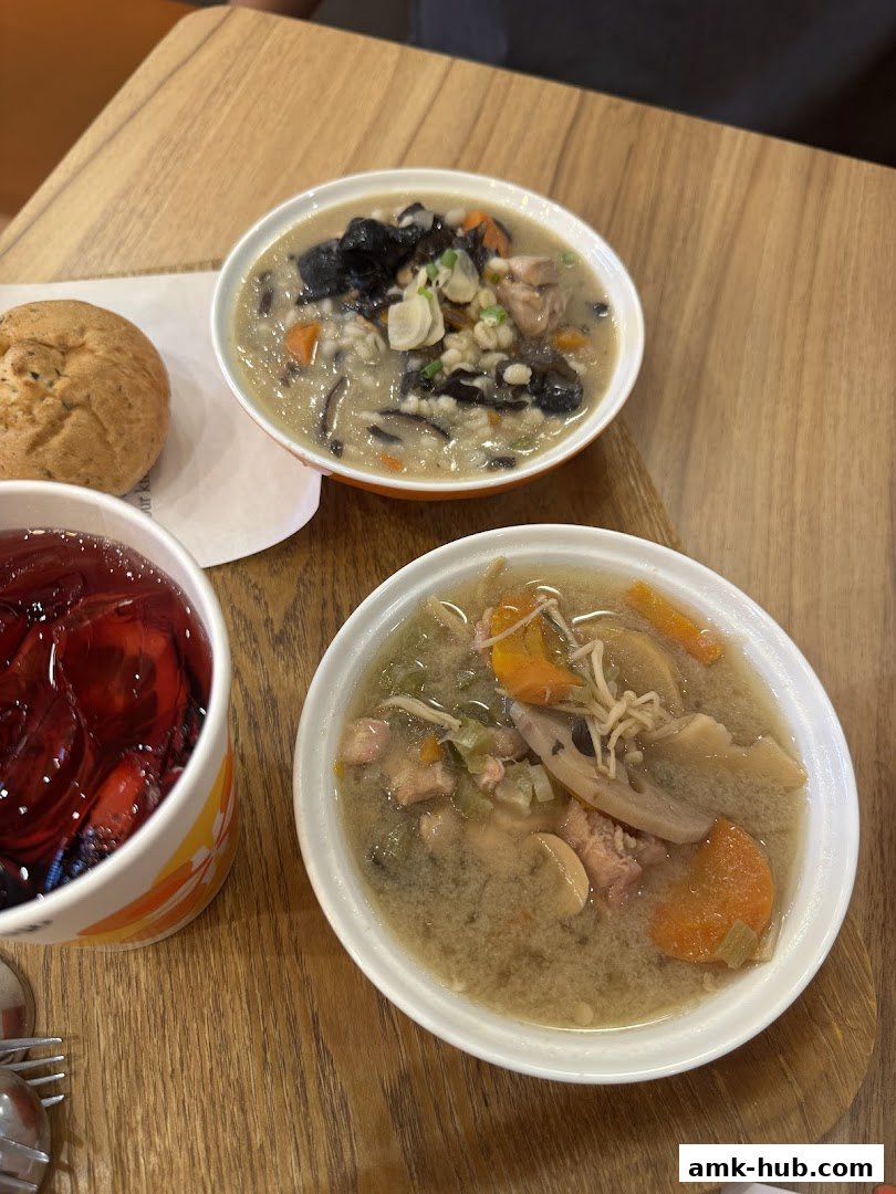 Two bowls of hearty soup and a drink are served on a wooden table.