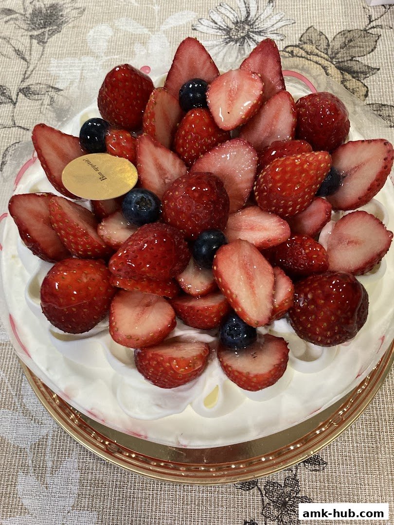 A beautifully decorated cake topped with fresh strawberries and blueberries.