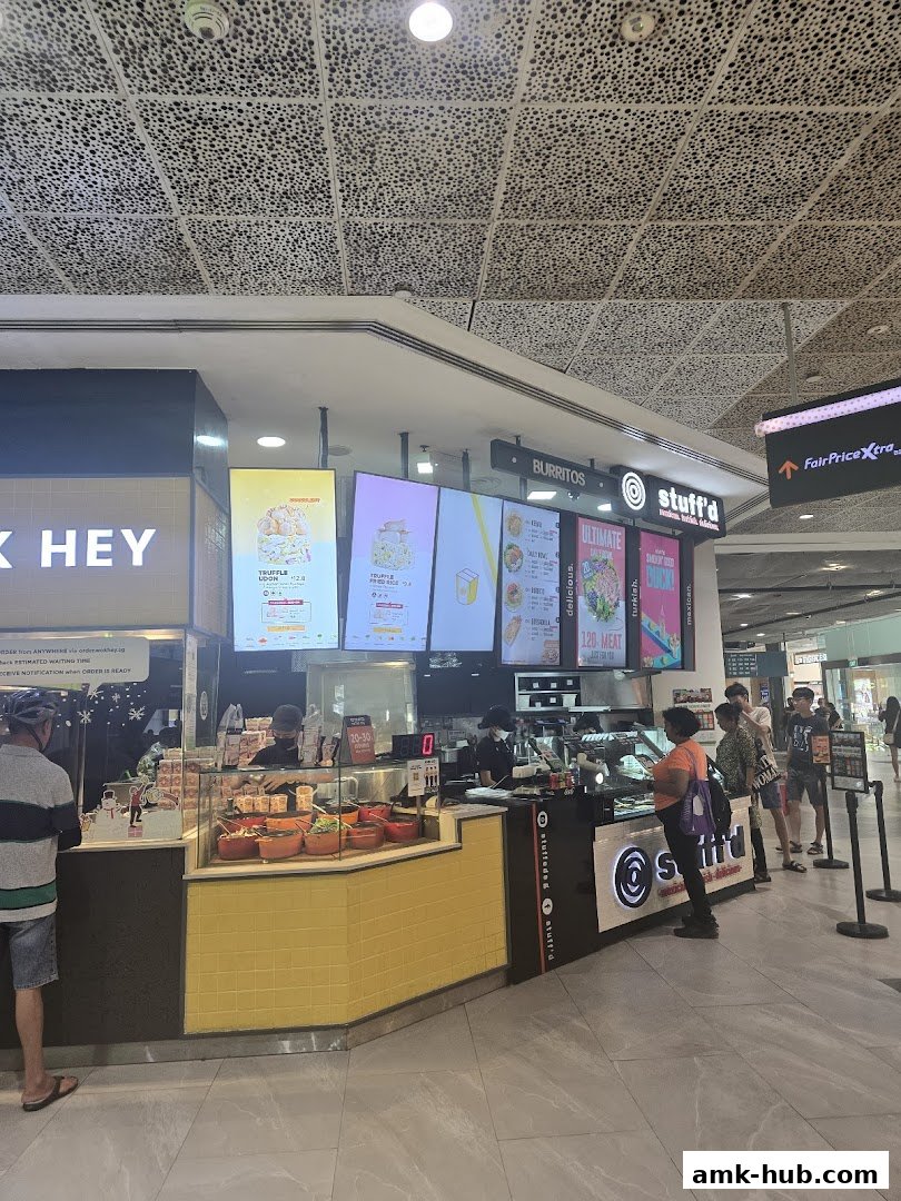 A busy WOK HEY and Stuff'd food stall with customers ordering and staff preparing food.