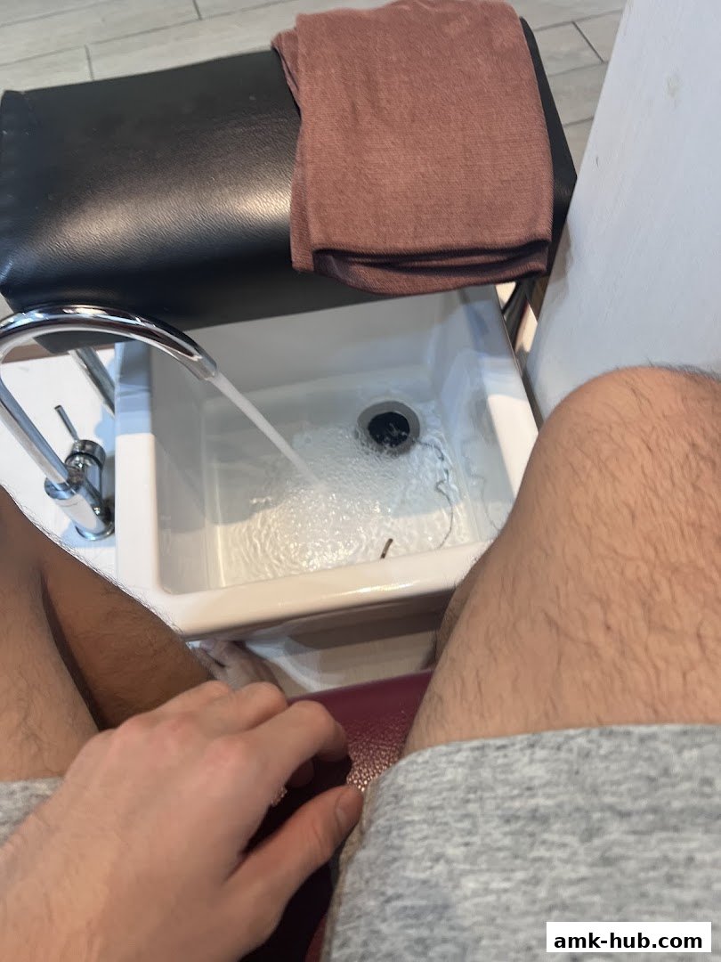 A person's legs and hand near a pedicure foot bath with running water.