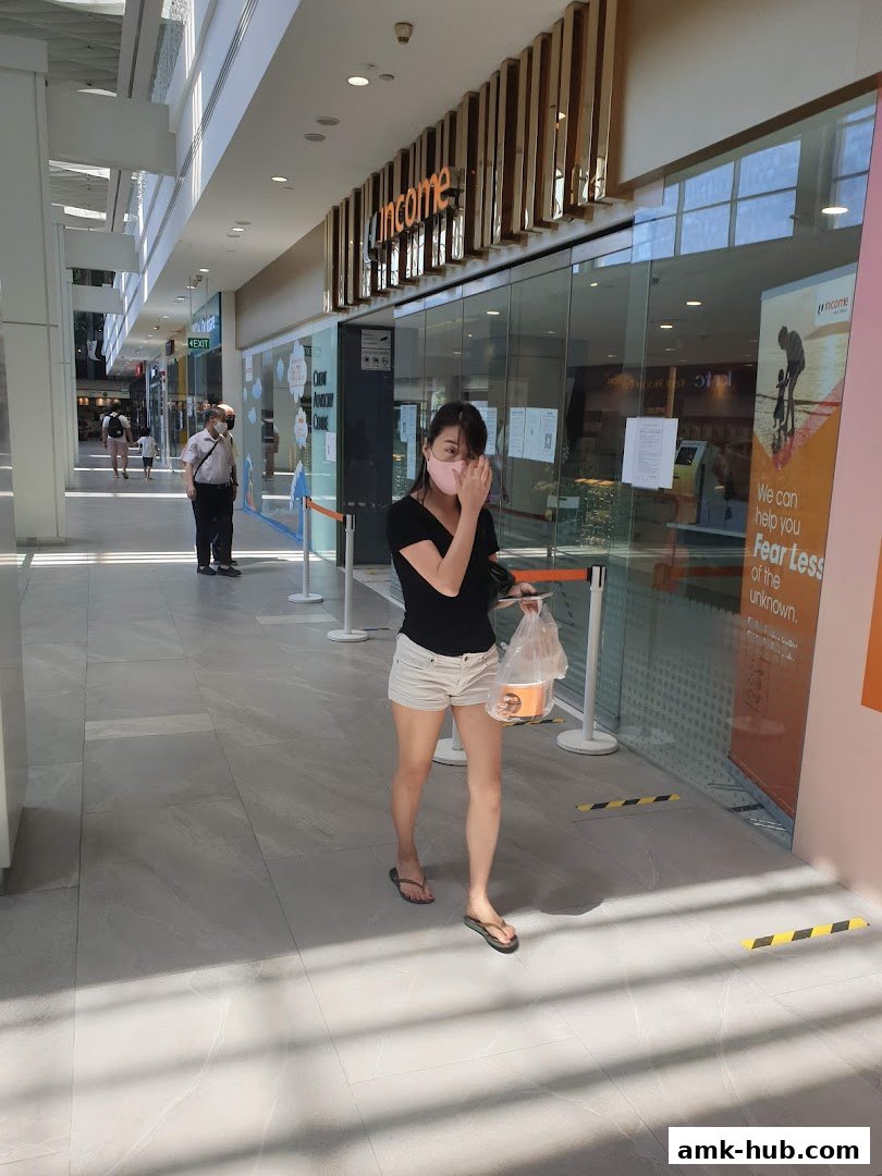 A woman walks past the Income Insurance Ang Mo Kio Branch storefront.