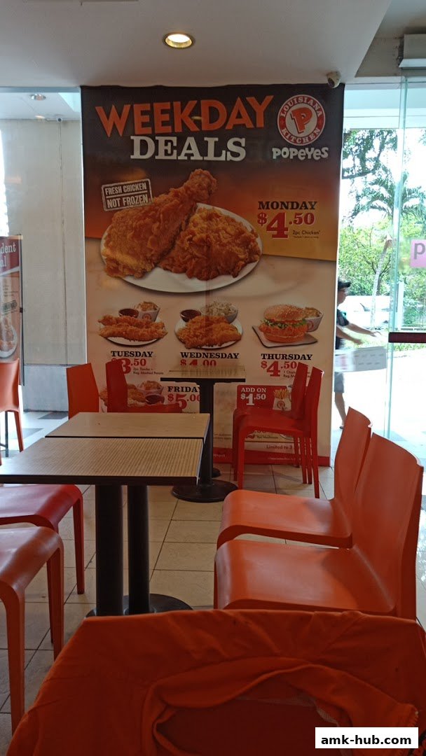 Popeyes restaurant interior featuring a large banner advertising weekday deals on fried chicken.