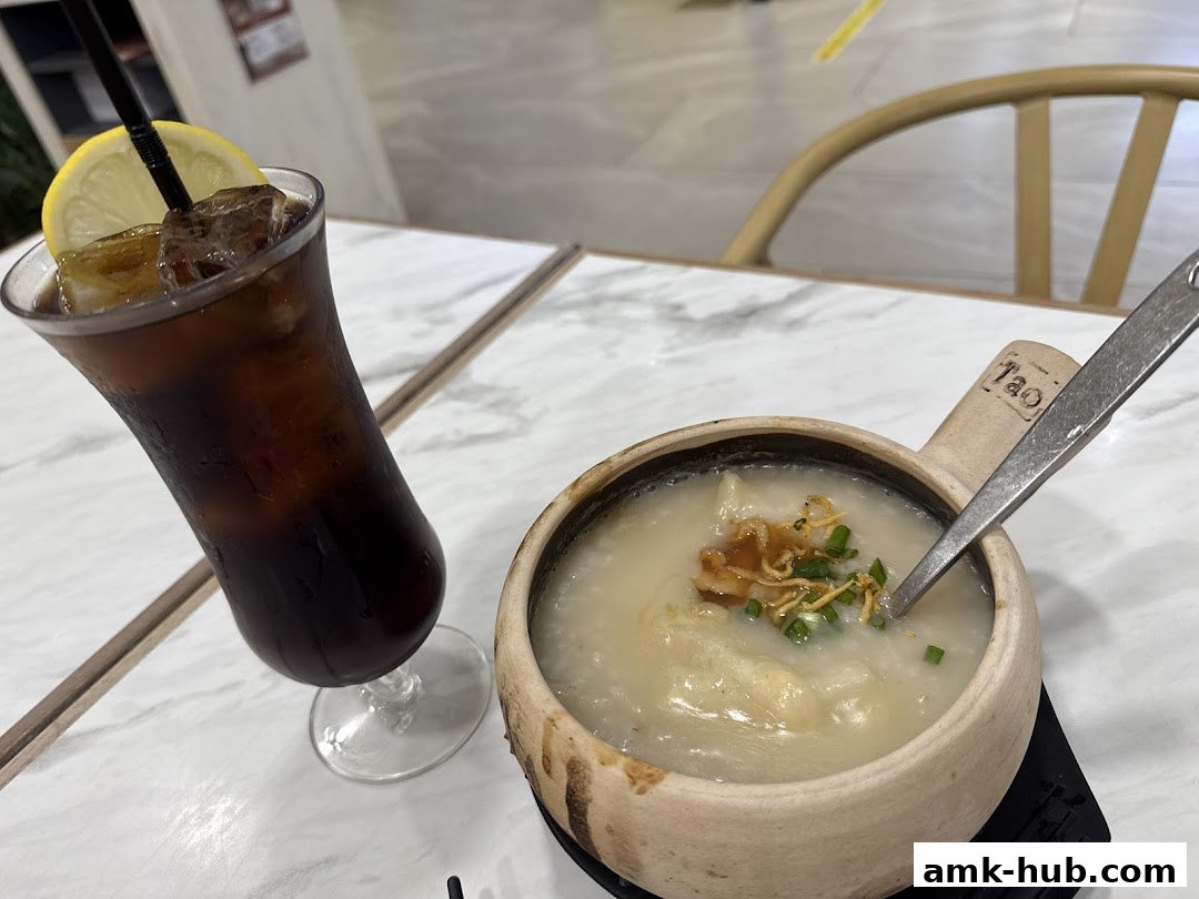A bowl of congee with a glass of iced coffee on a marble table.