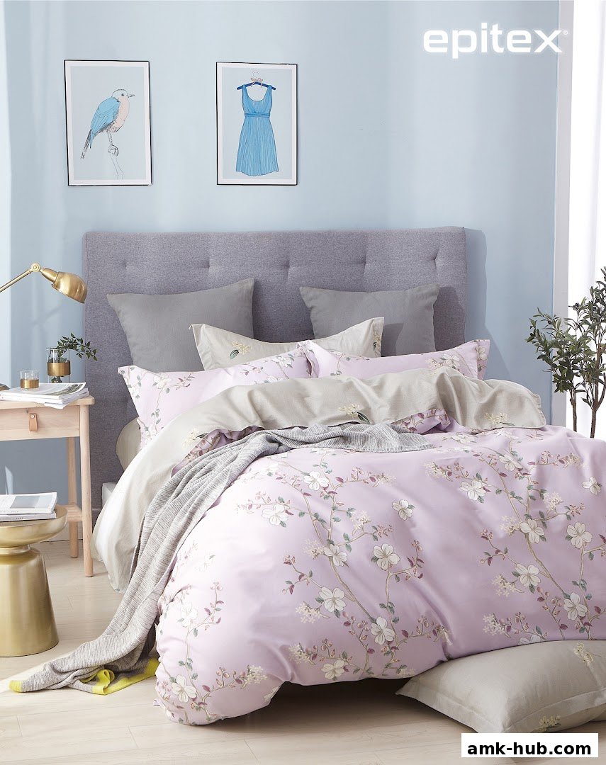 A beautifully made bed with floral patterned duvet and grey pillows.