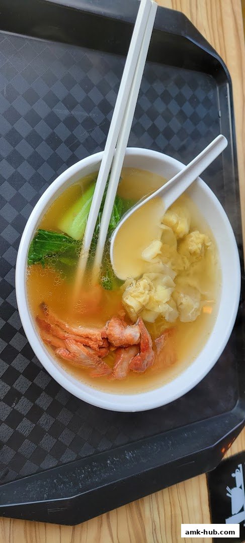 A bowl of wanton noodle soup with char siu pork and bok choy.