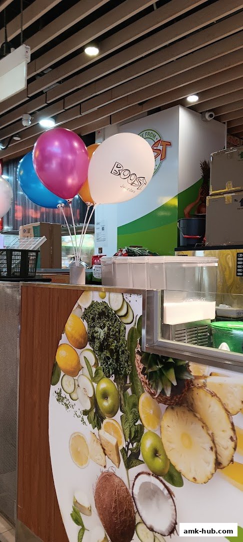 A Boost Juice counter decorated with colorful balloons and vibrant fruit imagery.