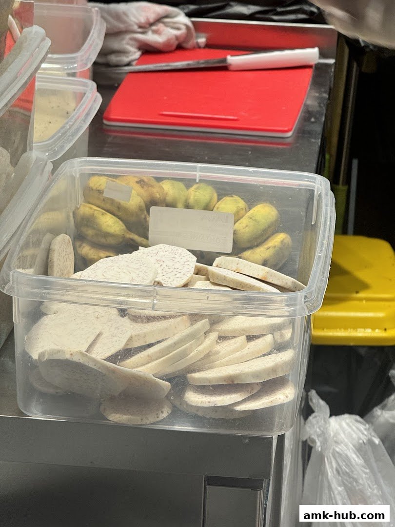 A clear plastic container filled with sliced taro root and bananas, ready for preparation.