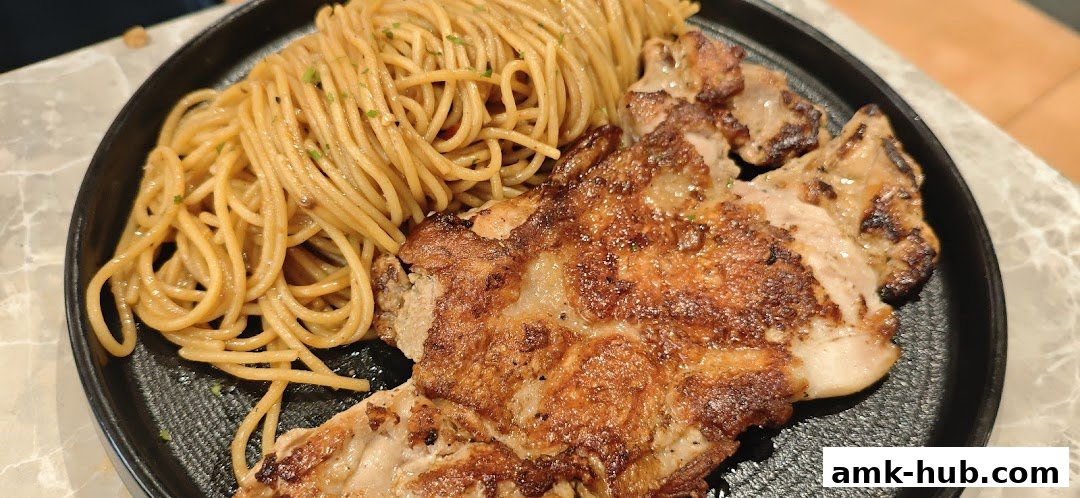 A close-up shot of a delicious meal featuring grilled chicken and spaghetti.