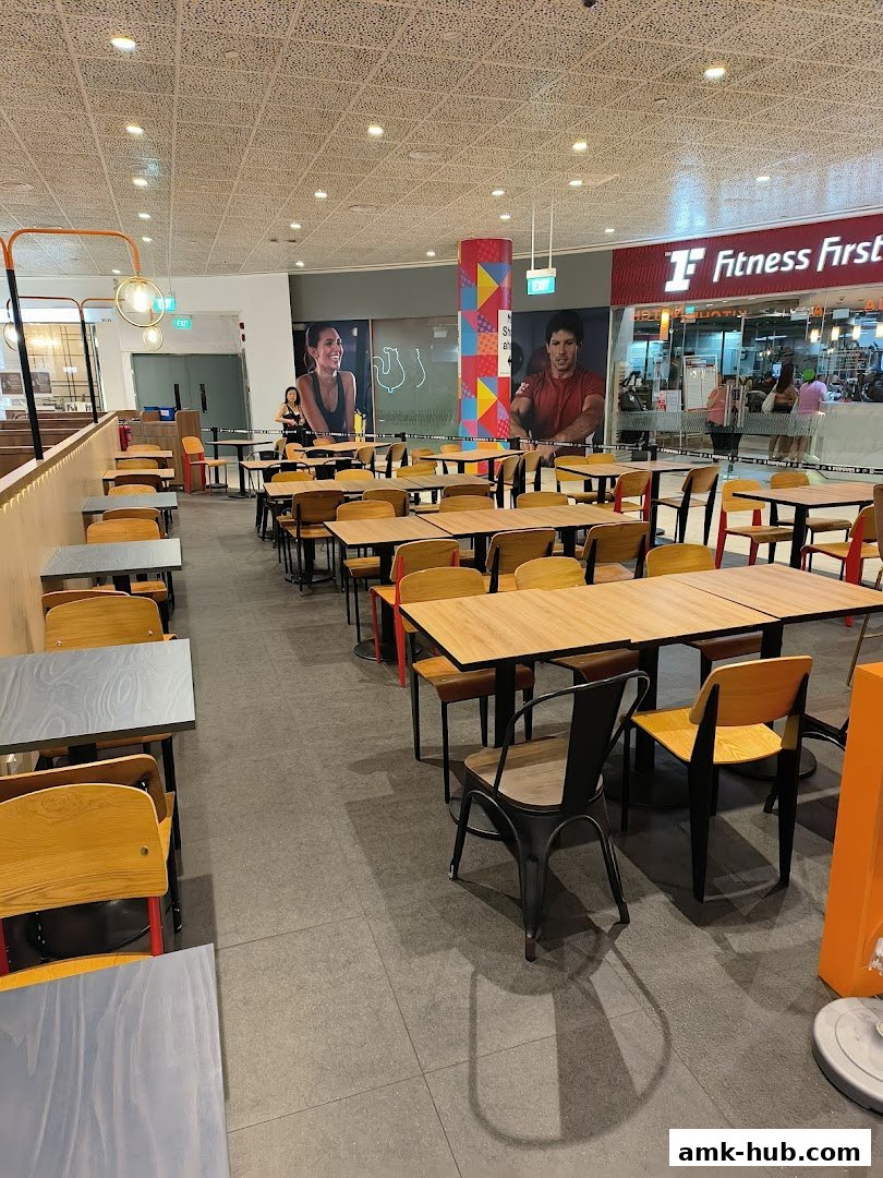 Interior view of a Popeyes restaurant with empty tables and chairs, and a Fitness First gym in the background.