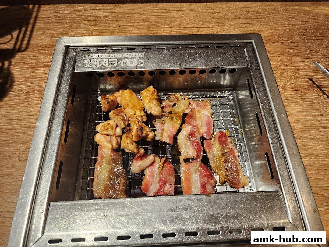 Assortment of grilled meats, including chicken and pork belly, cooking on a grill.