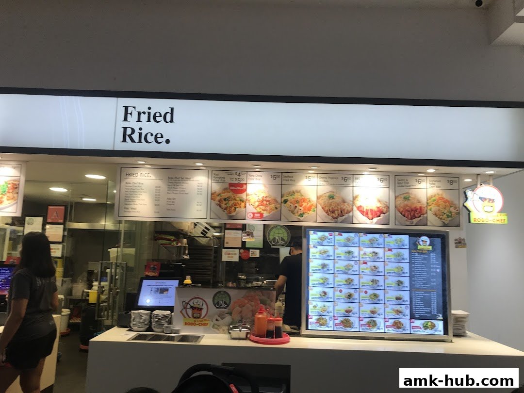 A food stall counter with a large digital menu displaying various fried rice dishes.