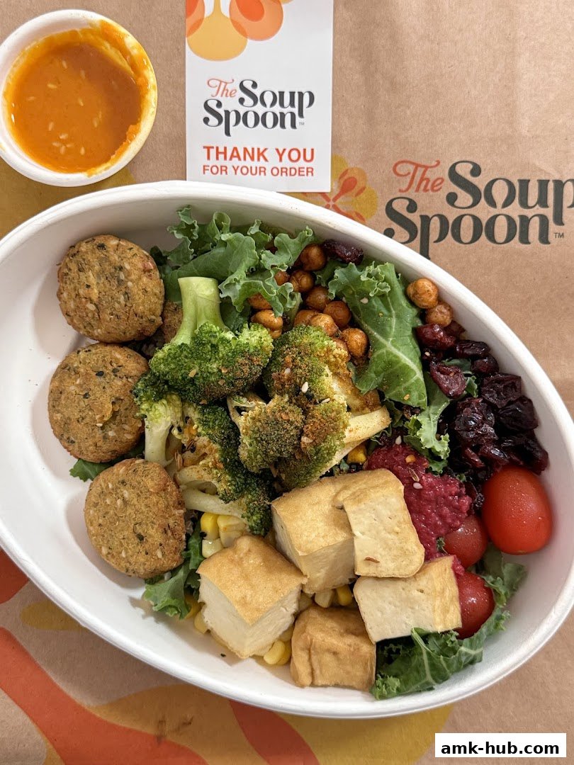 A healthy and colorful salad bowl with falafel, tofu, broccoli, and vegetables, served with dressing.