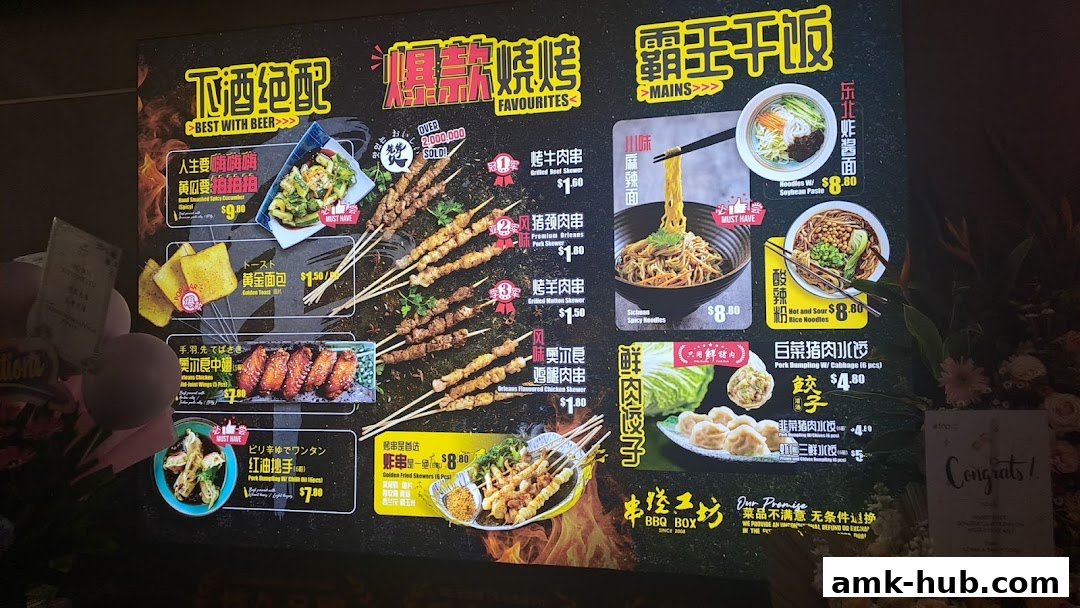 A brightly lit menu board for BBQ Box featuring skewers, noodles, and dumplings.